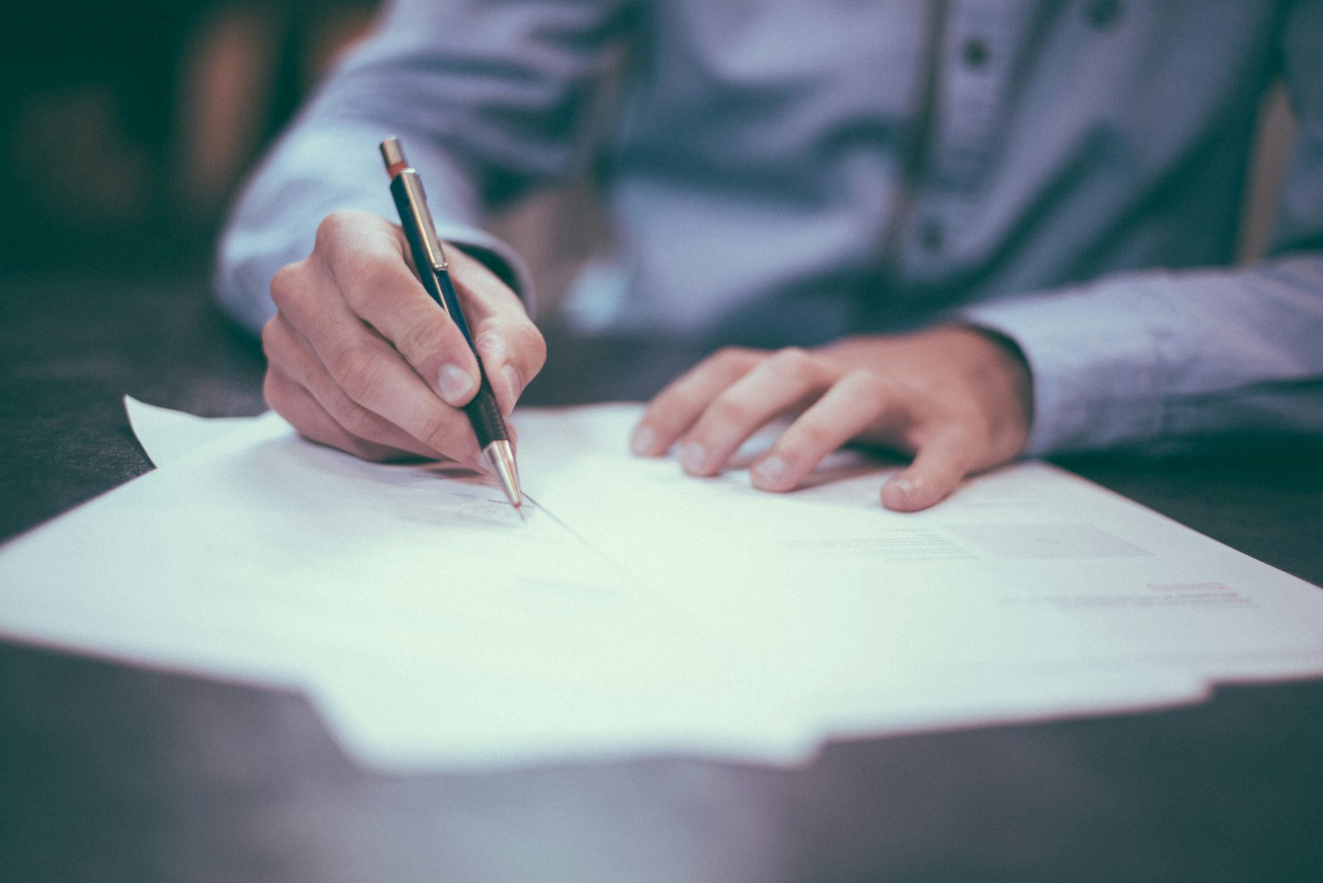 Person signing documents with pen